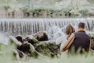 Poster - Back view of a couple sitting on the riverside in the park in autumn