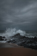 Vertical Shot Of A Sea Storm With Splashing Waves And Rocks Under A Cloudy Sky