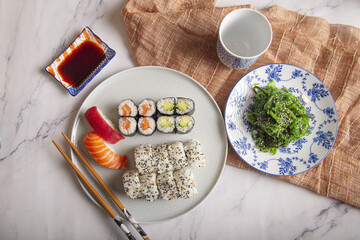 Poster - Japanese sushi nigiri and rolls, wakame seaweed salad, soy sauce and chopsticks on a marble table