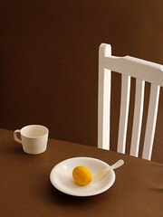 Poster - Ripe yellow lemon in white plate and white porcelain cup on a brown table with white chair near by