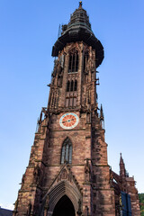 Wall Mural - Vertical shot of the bell tower of Freiburg Cathedral against blue sky on a sunny day in Germany