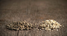 Two Heaps Of Raw Hemp Seeds, Whole And Shelled Against A Background Of Wood Texture.. Selective Focus.