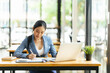 © PaeGAG - Portrait of Asian young female working on laptop and financial report at office.