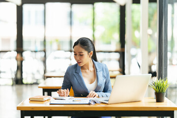 Wall Mural - Portrait of Asian young female working on laptop and financial report at office.