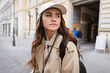 pretty woman in trench coat and baseball cap.