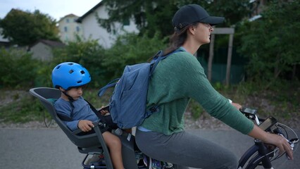 Wall Mural - Woman riding bicycle with toddler in back seat mother cyclist