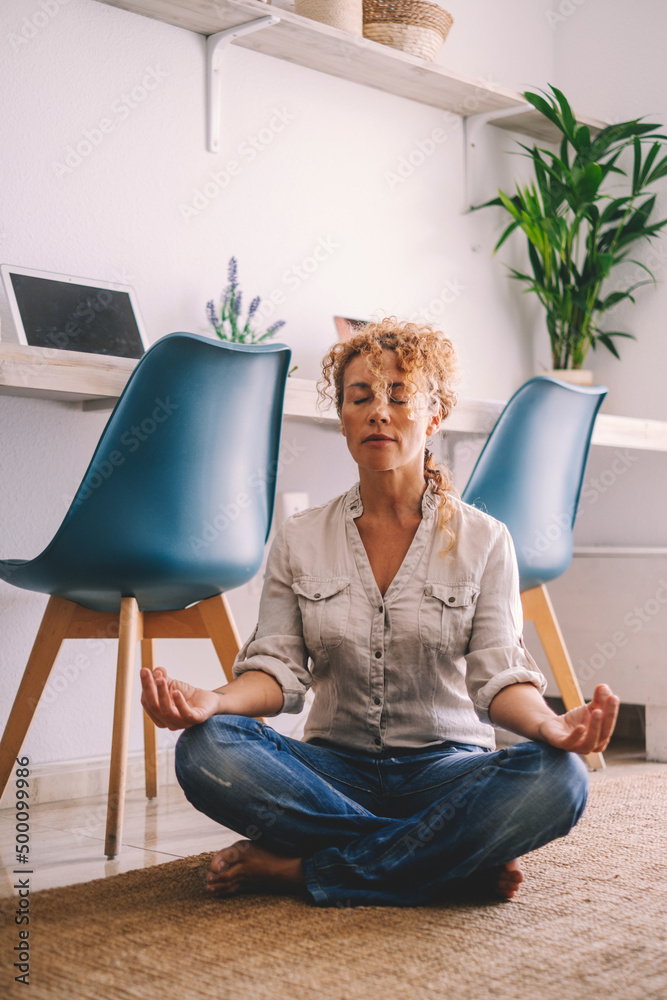 Woman sitting on the floor at home with casual clothes doing meditation ...