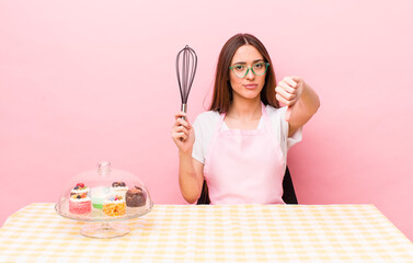 hispanic pretty woman feeling cross,showing thumbs down. home made cakes concept