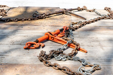A Ratchet Load Binder And Tie Down Chain On The Wooden Deck Of A Flatbed Truck Tailer.