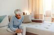 © Jelena Stanojkovic - A woman suffering from pain in the knee, closeup. Old age, health problem and people concept - mature woman suffering from pain in leg at home. Photo of senior woman holding the knee with the pain.