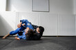 © Miljan Živković - Two brazilian jiu jitsu BJJ athletes training at the academy martial arts ground fighting sparring wear kimono gi sport uniform on the tatami mats sports jiujitsu and self-defense concept copy space
