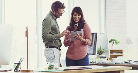 Aufkleber - I think thats a brilliant idea.Two cheerful young work colleagues standing talking while using a tablet in the office. Cheerful colleagues planning, brainstorming and laughing using a tablet