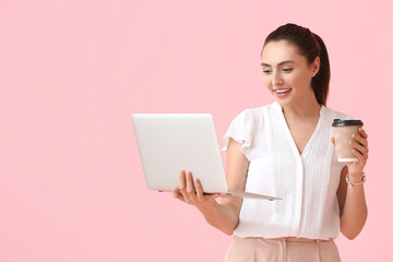 Poster - Pretty young businesswoman with laptop and cup of coffee on pink background