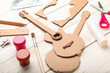 Cardboard guitar toy with materials on white wooden background, closeup
