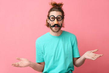 Funny young man in disguise on pink background. April fools' day celebration