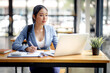 © David - Shot of an Asian young businesswoman working on a laptop computer in her workstation.Portrait of Business people employee freelance online marketing e-commerce telemarketing concept.