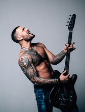 Expressive Young Man Playing Rock-n-roll Music On Electric Guitar. Excited Sexy Man With Electric Guitar. Instrument On Stage And Band. Strong, Muscular, Muscles Guy. Music Concept. Man Playing Guitar