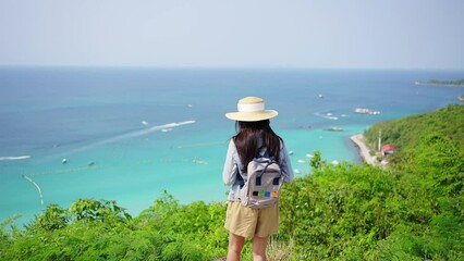 Wall Mural - 4K Young beautiful Asian woman with backpack solo travel on tropical island mountain peak in summer sunny day. Cheerful female relax and enjoy outdoor lifestyle in summer beach holiday vacation trip