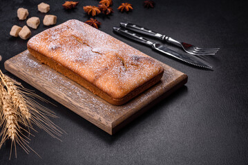 Baked rectangular cupcake with raisins and chocolate on a dark concrete background