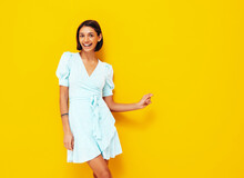 Young Beautiful Smiling Female In Trendy Summer Blue Dress. Sexy Carefree Woman Posing Near Yellow Wall In Studio. Positive Model Having Fun. Cheerful And Happy. Isolated