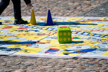 people outdoors on a sunny day on the pavement playing an enlarged board game