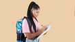 © PintoArt - Young african american teenage student woman in shirt backpack holds pen notebook writing lecture isolated on beige background,Education in high school university college concept