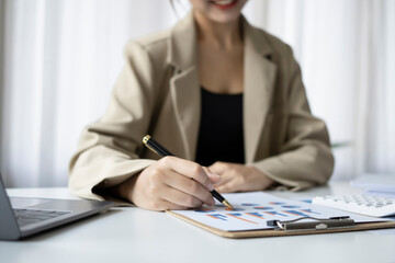 Wall Mural - Cropped shot businesswoman holding pen and checking financial reports on white office desk.