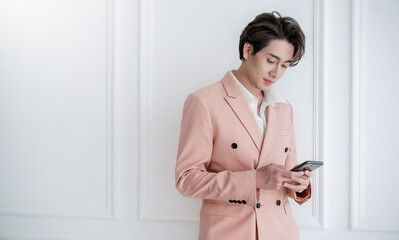 portrait of korean asian handsome smile friendly business model man in pink suit text on smart phone