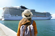 © zigres - Cruise vacation. Rear view of tourist girl with backpack and hat standing in front of big cruise ship.