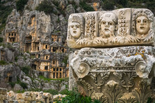 Stone Theater Faces And Masks In Myra Ancient City. Lycian Rock Tombs In Background. Demre, Antalya