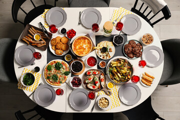 Brunch table setting with different delicious food and chairs indoors, top view