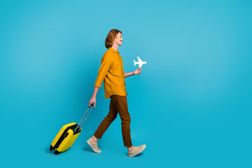 Poster - Full size profile side photo of man leaving on weekend travel go with luggage hold plane card isolated on blue color background