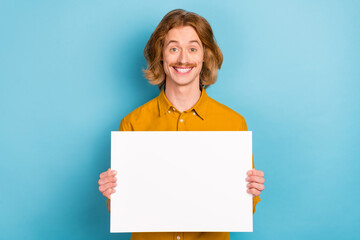 Sticker - Portrait of attractive cheerful long-haired guy holding in hands copy space banner isolated over bright blue color background