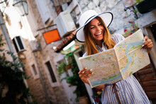 Young Female Tourist With Map Looking For A Way On Summer Vacation