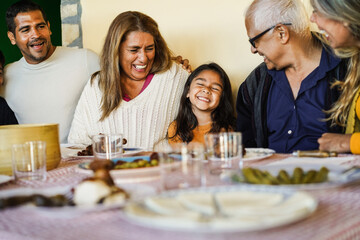 Wall Mural - Happy latin family having fun eating together home - Focus on girl face