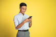 © Odua Images - happy asian young man looking at the screen of a mobile phone on isolated background