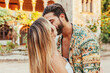 Young attractive couple in love kissing in front of villa castle during summer holiday vacations. Human relationships.