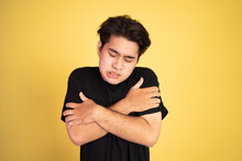 Asian Young Man Shivering While Holding His Two Arms Hug Himself On Isolated Background