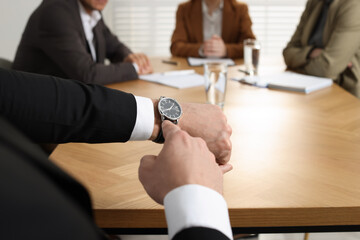 Poster - Businessman pointing on wrist watch while scolding employee for being late in office, closeup