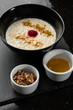 © MONIUK ANDRII - Semolina porridge for breakfast oat with nuts in black bowl served with honey isolated on black stone background. Homemade food. Tasty breakfast.