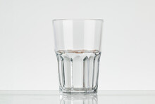 Faceted Glass Of Water, Half Filled. Translucent Glass On A White Background.