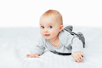 seven month old baby child sitting on bed. cute smiling little infant girl on white soft blanket. ch