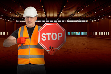 Poster - Builder warns of danger. Inspector in orange vest demonstrates stop sign. Concept of danger of using industrial building. Security inspector points to word Stop. Builder inside dark hangar.