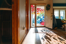 A Colorful Rainbow Of Cut Out Hearts Decorate A Backlit Front Door And Casts Shadows On The Floor
