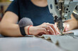 © Aleksandr - Close up view of sewing process. Female hands stitching white fabric on professional manufacturing machine at workplace. Seamstress hands holding textile for dress production.