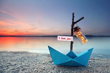 Wall Mural - romantic evening - magical blue paper boat with lantern at the beach