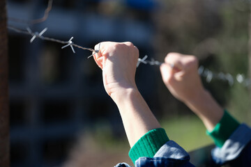 Woman holding hands on barbed wire closeup