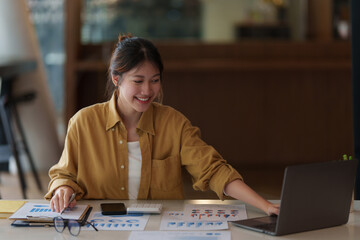 Wall Mural - Consult financial concept. Business woman pointing at papwework and using laptop computer.