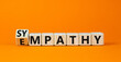 Sympathy or empathy symbol. Turned wooden cubes and changed the concept word Empathy to Sympathy. Beautiful orange table orange background. Copy space. Psychological sympathy or empathy concept.