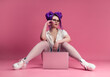 © rotozey - sexy girl with glasses and purple hair with a laptop on a pink background